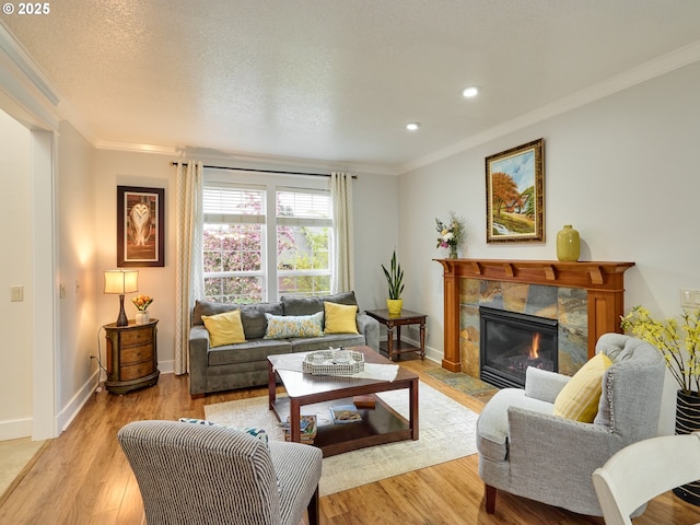 living room featuring light wood-type flooring, ornamental molding, a tile fireplace, and baseboards