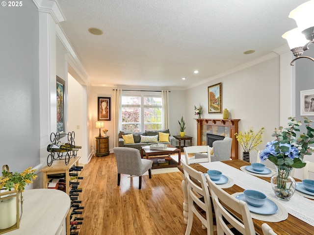 dining space featuring a fireplace, crown molding, and light wood-style floors