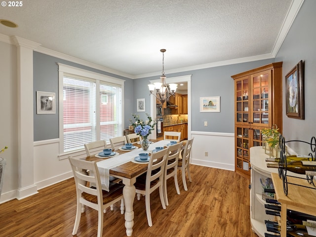 dining area featuring a chandelier, ornamental molding, a textured ceiling, and wood finished floors