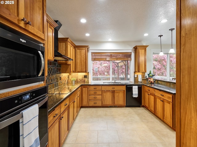 kitchen with brown cabinetry, black appliances, a sink, and plenty of natural light