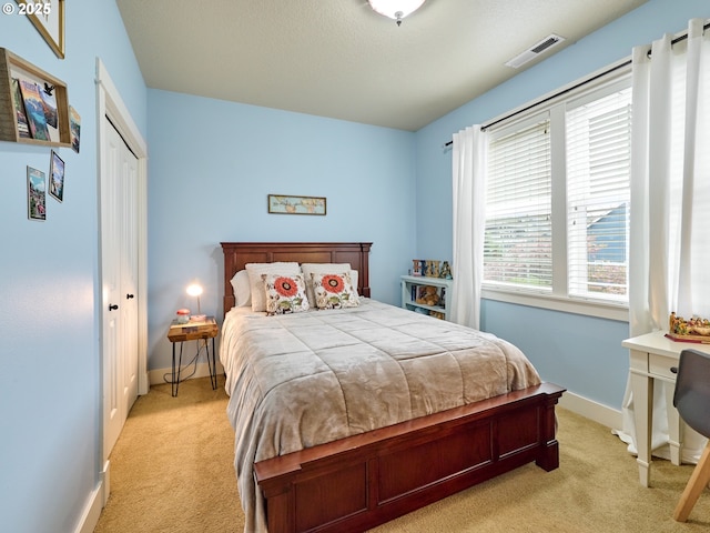 bedroom with baseboards, a closet, visible vents, and light colored carpet