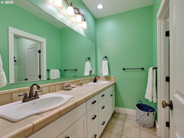 bathroom featuring baseboards, tile patterned flooring, double vanity, and a sink