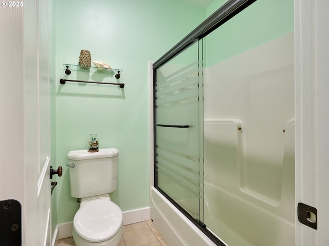 bathroom featuring tile patterned floors, toilet, baseboards, and shower / bath combination with glass door