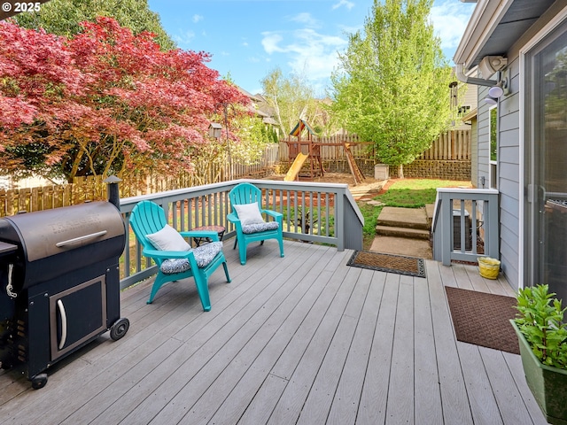 wooden terrace with a fenced backyard, a playground, and a grill