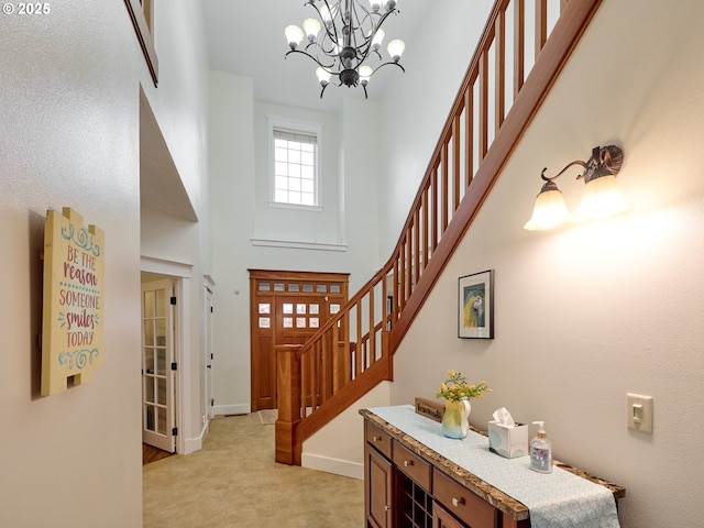 foyer with a notable chandelier, baseboards, a towering ceiling, and stairs