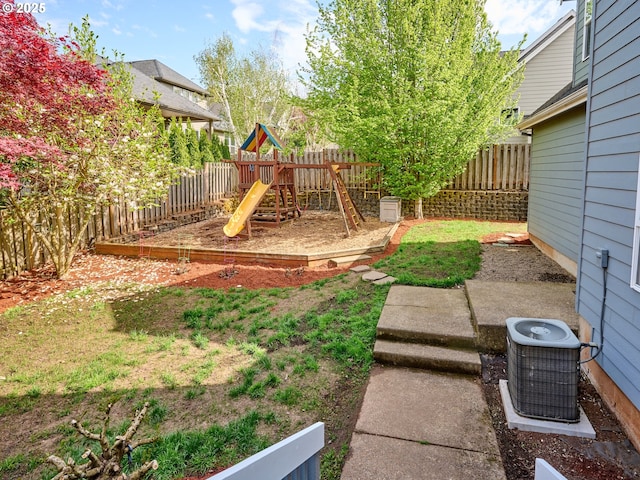 view of yard with central AC unit, a playground, and a fenced backyard