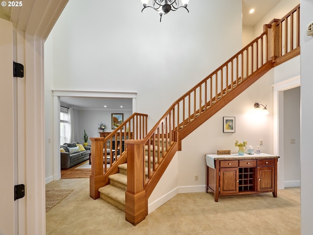 stairway featuring a chandelier, a towering ceiling, baseboards, and tile patterned floors