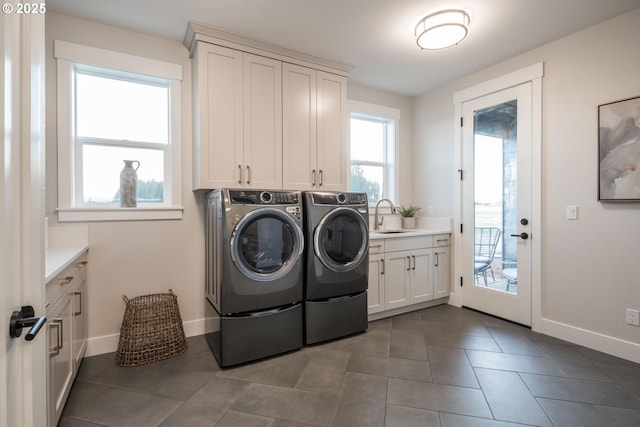 washroom with cabinet space, separate washer and dryer, baseboards, and dark tile patterned flooring