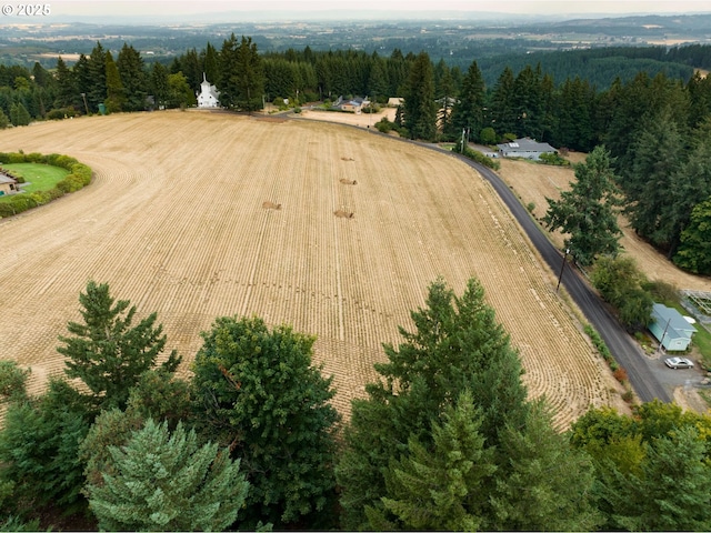 aerial overview of property's location with rural landscape, rows of crops, and a forest