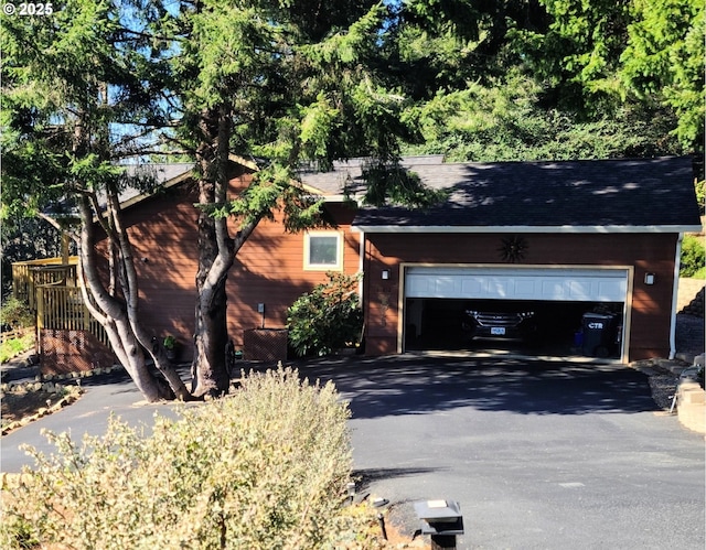 view of front facade with a garage, aphalt driveway, and roof with shingles