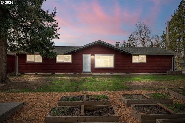 back of property featuring a lawn and a vegetable garden