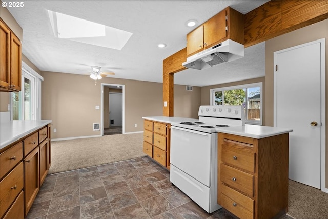 kitchen with a skylight, electric stove, light countertops, and under cabinet range hood