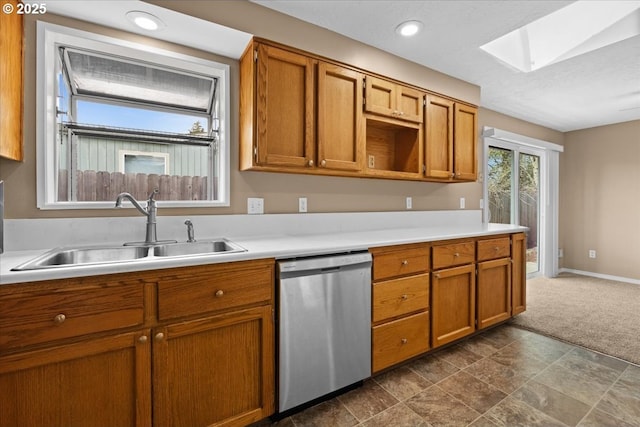 kitchen with a skylight, light countertops, a sink, and stainless steel dishwasher