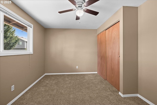 unfurnished bedroom with carpet floors, a closet, ceiling fan, and baseboards