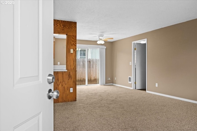 carpeted empty room with ceiling fan, a textured ceiling, and baseboards