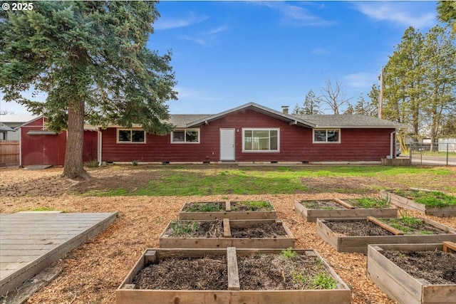 back of property with crawl space, a vegetable garden, fence, and a lawn