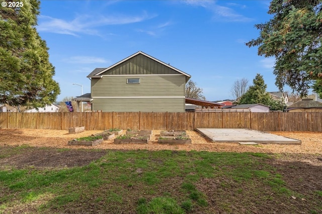 view of side of property featuring a patio area, a vegetable garden, and fence