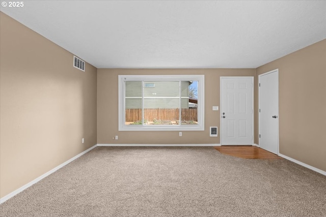 empty room featuring carpet, visible vents, and baseboards