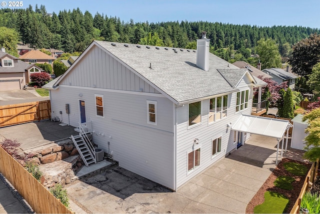 13212 SE Terra Cascade Dr, Happy Valley, OR 97086 - back of house with roof with shingles, a forest view, board and batten siding, and a chimney