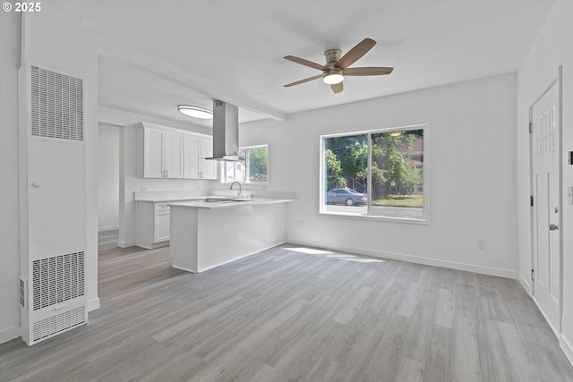 115 E Sheridan St, Newberg, OR 97132 - kitchen with wall chimney range hood, a heating unit, light countertops, ceiling fan, and white cabinets