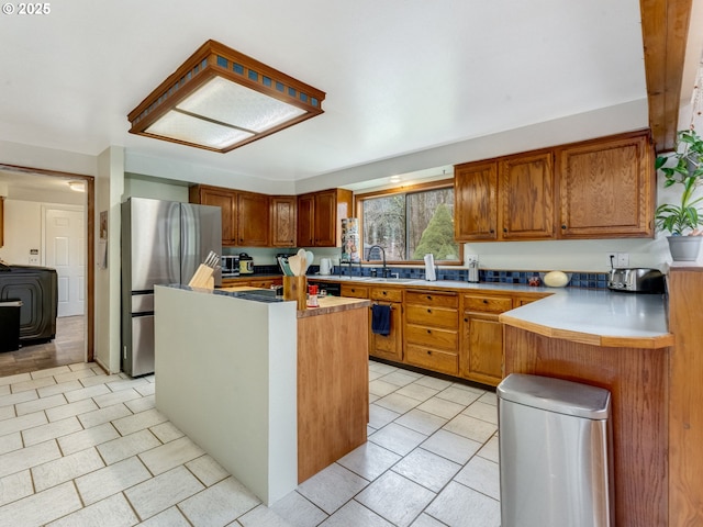 kitchen featuring brown cabinetry, a center island, and freestanding refrigerator