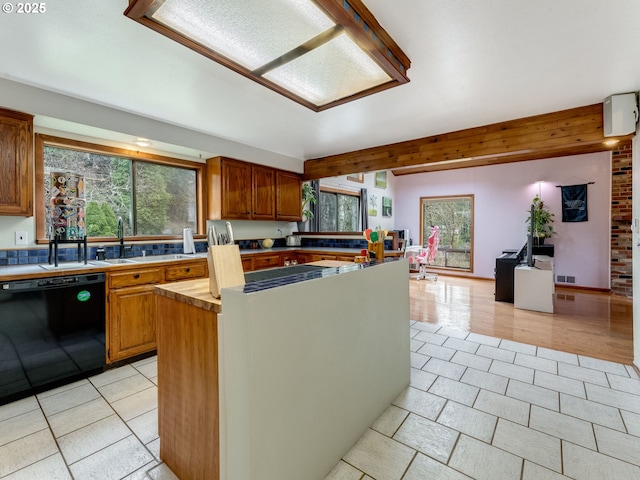 kitchen with black dishwasher, a healthy amount of sunlight, visible vents, and a center island