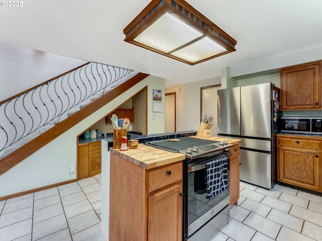 kitchen with light tile patterned floors, butcher block countertops, brown cabinets, and stainless steel appliances