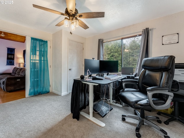 carpeted home office with a textured ceiling and a ceiling fan