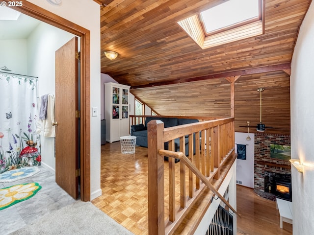 hall with parquet floors, vaulted ceiling with skylight, wood ceiling, and an upstairs landing