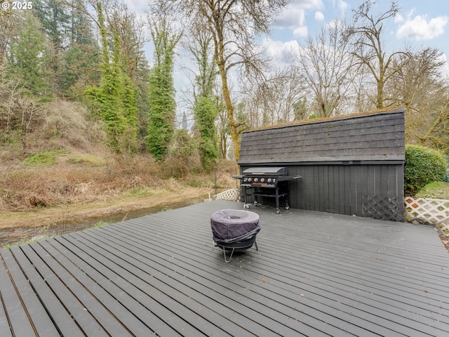 wooden deck featuring an outdoor structure and a grill