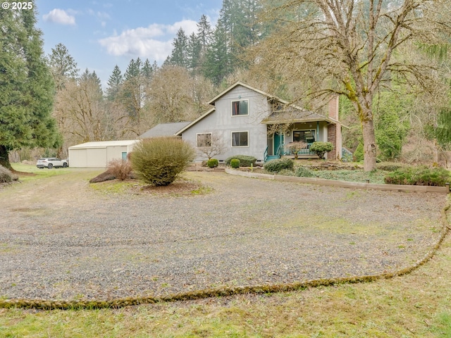 view of front of home featuring a garage, gravel driveway, and covered porch