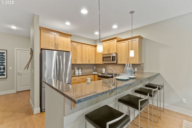 16185 NW Ashfield Dr, Beaverton, OR 97006 - kitchen with appliances with stainless steel finishes, a peninsula, dark stone countertops, baseboards, and a breakfast bar