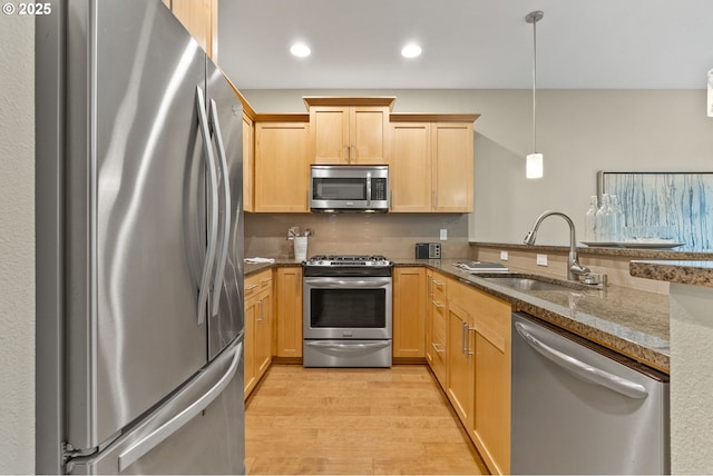 16185 NW Ashfield Dr, Beaverton, OR 97006 - kitchen featuring appliances with stainless steel finishes, a sink, light wood finished floors, dark stone countertops, and backsplash