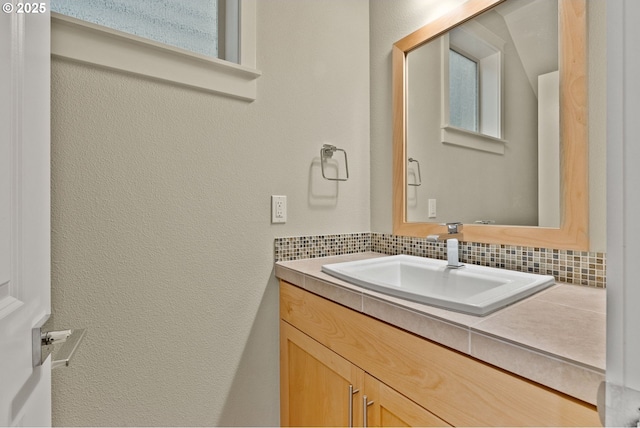 16185 NW Ashfield Dr, Beaverton, OR 97006 - bathroom featuring vanity, a textured wall, and decorative backsplash