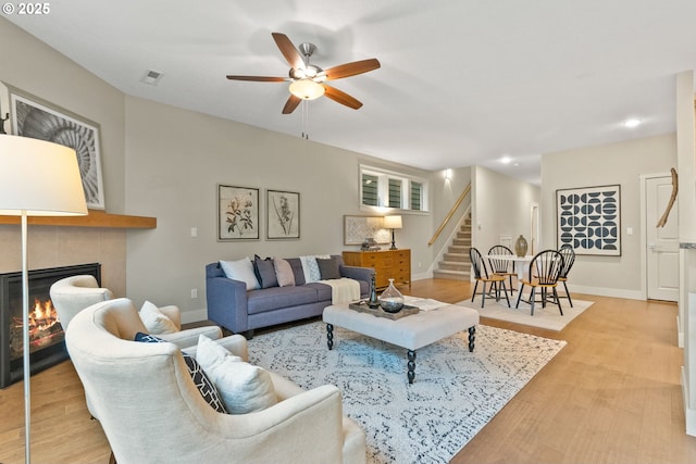 16185 NW Ashfield Dr, Beaverton, OR 97006 - living area featuring stairs, a ceiling fan, a tiled fireplace, light wood-type flooring, and recessed lighting