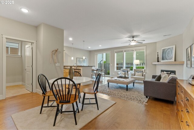 16185 NW Ashfield Dr, Beaverton, OR 97006 - dining area featuring light wood finished floors, a ceiling fan, a fireplace, baseboards, and recessed lighting