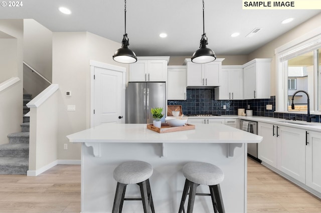 8510 NE 134th Ave Lot 87, Vancouver, WA 98685 - kitchen featuring appliances with stainless steel finishes, a sink, decorative backsplash, light wood-style floors, and white cabinetry
