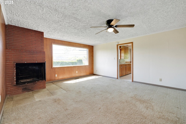 unfurnished living room with baseboards, a ceiling fan, a textured ceiling, and a fireplace