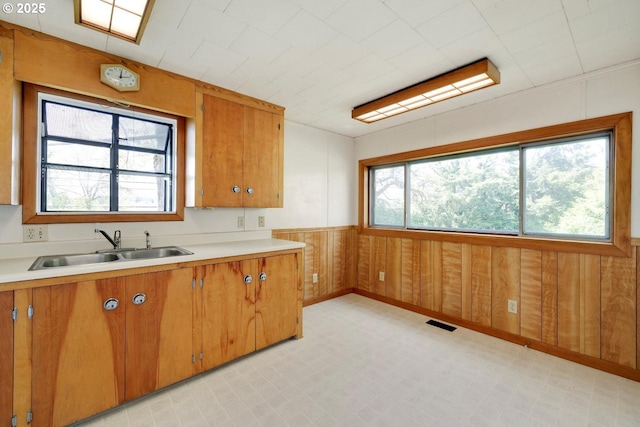 kitchen with a sink, light floors, brown cabinetry, and light countertops