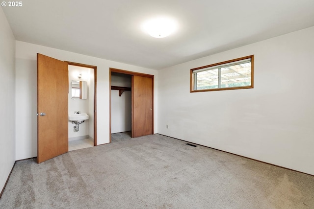 unfurnished bedroom featuring light carpet, a closet, and visible vents