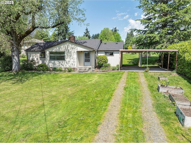 back of house featuring a yard, driveway, a chimney, and a carport