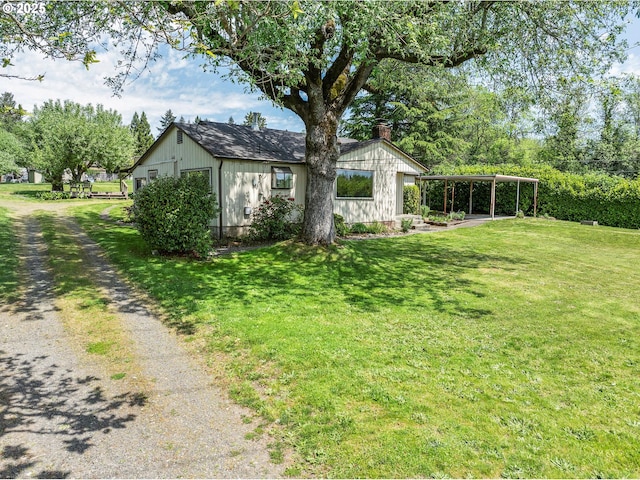 view of side of home with a lawn, a detached carport, and a chimney