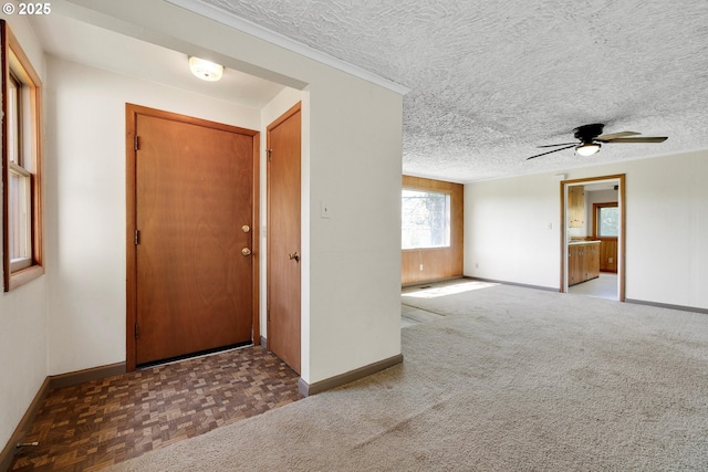 foyer featuring a textured ceiling, baseboards, and a ceiling fan