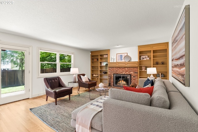 living area featuring a textured ceiling, a brick fireplace, and light wood-type flooring