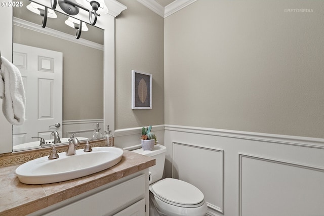 half bath featuring crown molding, vanity, wainscoting, and toilet