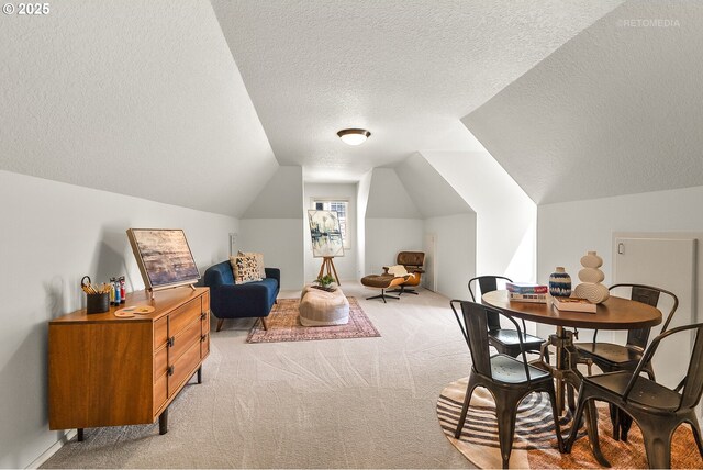 dining space featuring a textured ceiling, light colored carpet, and vaulted ceiling