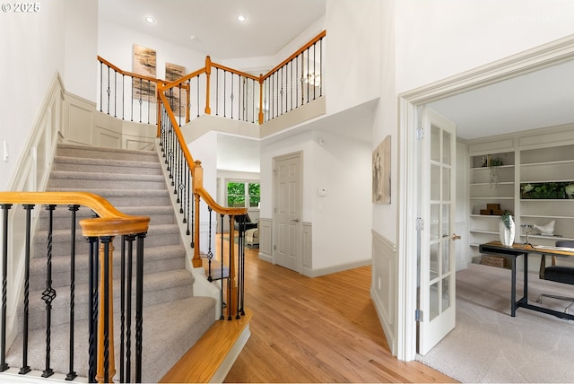stairway featuring wood finished floors, recessed lighting, french doors, and a high ceiling
