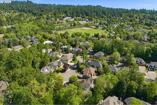 aerial view of property and surrounding area with a forest and nearby suburban area