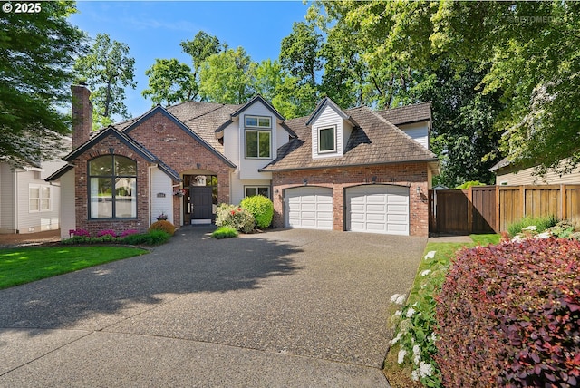 view of front facade with brick siding, driveway, fence, and an attached garage