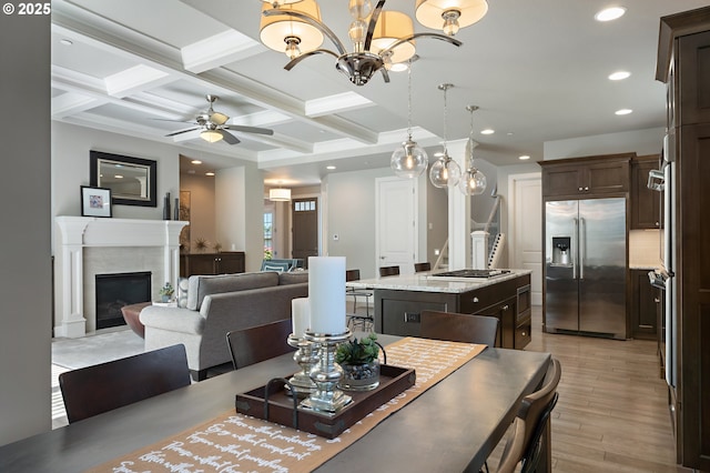 dining space with a high end fireplace, beam ceiling, light wood-style floors, coffered ceiling, and recessed lighting